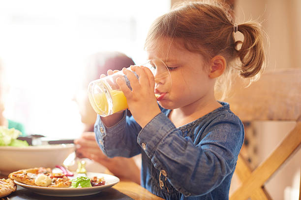 little girl drinking juice at dinner