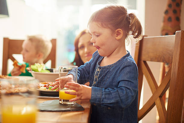 istock little girl drinking juice at dinner 499283322