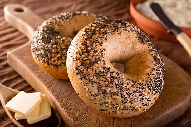 Freshly baked homemade bagels with onion, sesame seed, poppy seed, cream cheese, and butter.