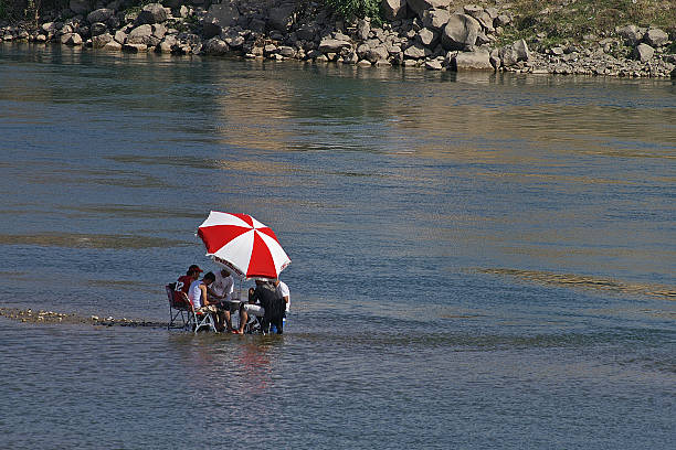 People enjoy life sitting in river Euphrate in Syria Raqqa, Syria - 7th May, 2010: some people sitting on chairs under an umbrella in the river Euphrate near Raqqa in Syria. euphrates syria stock pictures, royalty-free photos & images