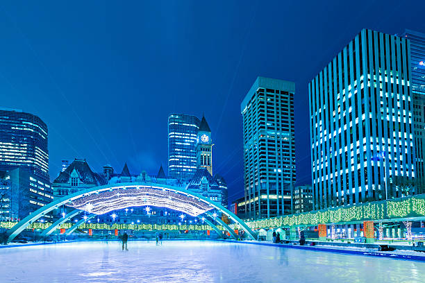 Photo of the Nathan Phillips Square skating rink in downtown Toronto, Ontario, Canada on a winter evening, night.