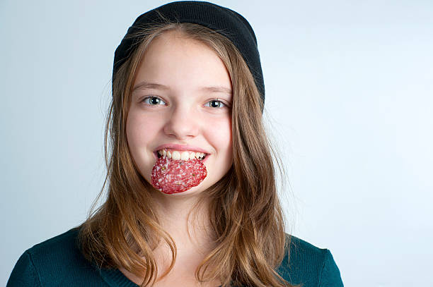 Portrait of a little girl with a piece of sausage. stock photo