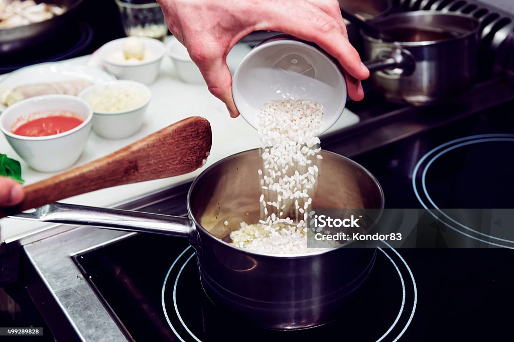 Chef is pouring rice in stewpan Chef is pouring rice in stewpan, toned image Rice - Food Staple Stock Photo