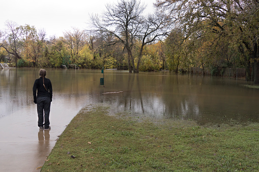 After two days and nights of heavy November rains, Little Bear Creek overflowed its banks and flooded making Sparger Park a lake, preventing a young woman in a pony tail from running on the trail in the suburb of Colleyville, in Dallas Texas.