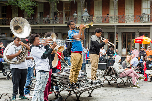 New Orleans, USA - November 8, 2015: A group of young men play jazz music as people sit in Jackson Square in the French Quarter of New Orleans, Louisiana.