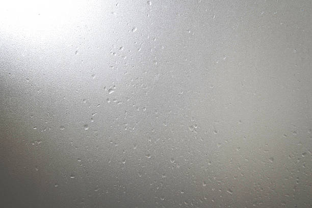 Frosted glass with water drops and bright light at corner