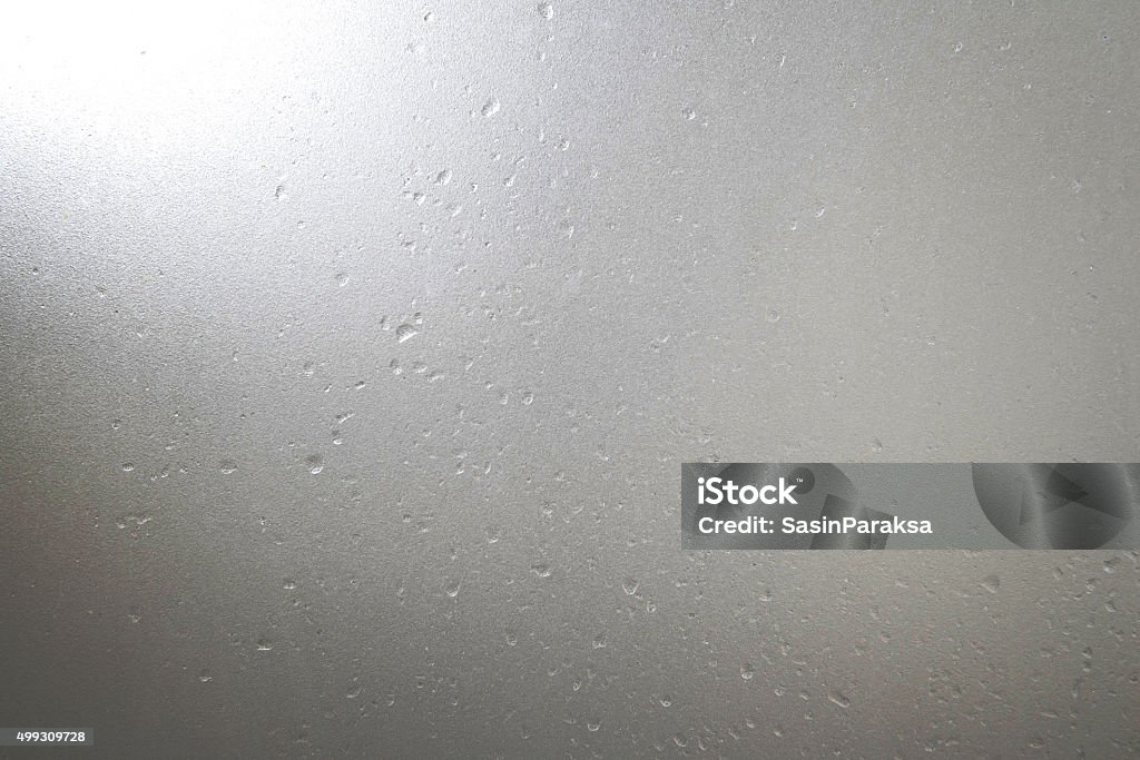 Frosted glass with water drops and bright light at corner Glass - Material Stock Photo