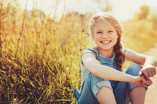 happy child girl in jeans overall playing on sunny field, summer outdoor lifestyle, cozy moodhappy child girl in jeans overall playing on sunny field, summer outdoor lifestyle, cozy mood