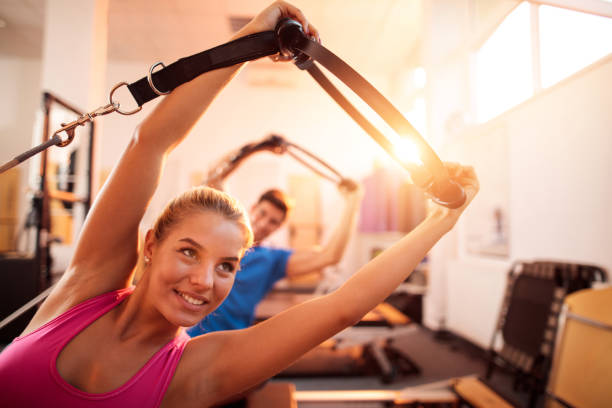 istock Young athletes doing stretching exercises on Pilates machines. 499315600
