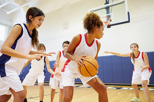 female high school basketball team playing game - meisjes stockfoto's en -beelden