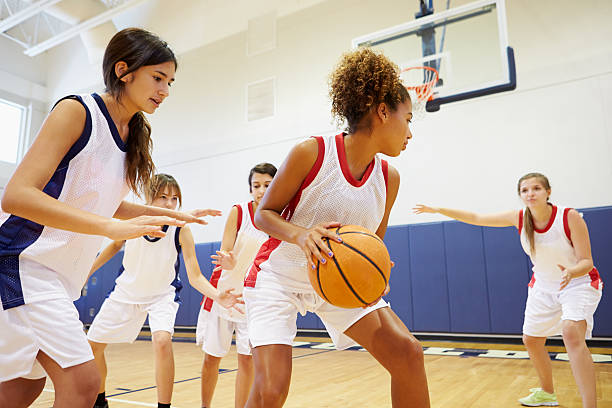 Female High School Basketball Team Playing Game Female High School Basketball Team Playing Game In Gymnasium basketball sport stock pictures, royalty-free photos & images