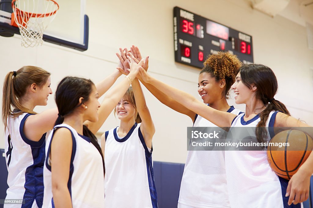 Female High School Basketball Team Having Team Talk Female High School Basketball Team Having Team Talk Putting Hands In Basketball - Sport Stock Photo