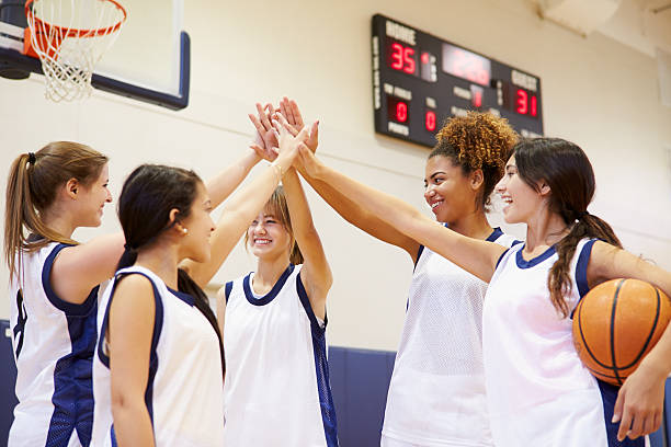 Female High School Basketball Team Having Team Talk Female High School Basketball Team Having Team Talk Putting Hands In teenagers only teenager multi ethnic group student stock pictures, royalty-free photos & images