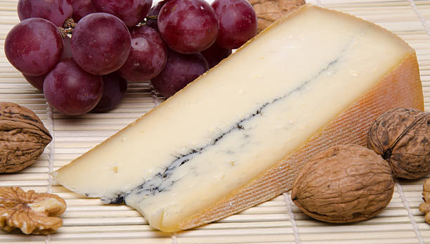 französische morbier käse auf einem stroh-tischset - morbier stock-fotos und bilder
