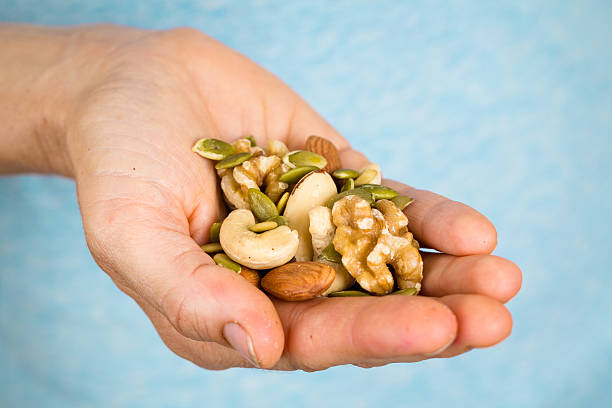 Hand holding a variety of nuts and seeds A hand holding a wide variety of nuts and seeds. palm fiber stock pictures, royalty-free photos & images
