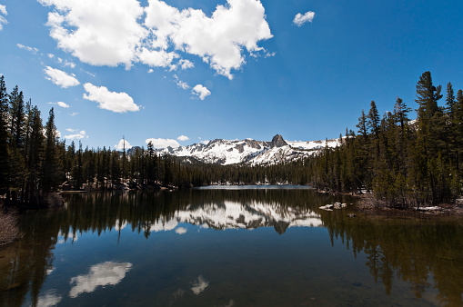 Clouds, trees and mountains reflected off of Lake Mary in Mammoth Lakes, CA