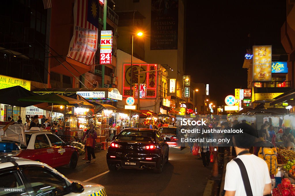 Night in Chinatown of Kuala Lumpur Kuala Lumpur, Malaysia - September 8, 2012: View along street of Chinatown of Kuala Lumpur in night. Some cars and taxis are in street. People are walking along street and shops. There are inhabitants and tourists. Nightlife scene. Adult Stock Photo