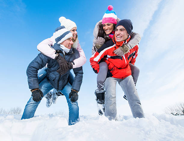 istock Smiling men piggybacking their girlfriends on snow. 499335368