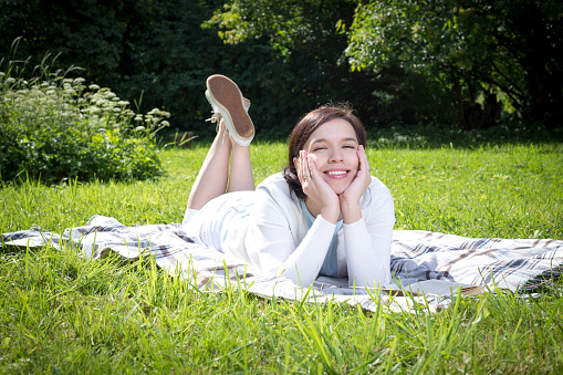 young attractive woman laying on the blanket and reading a book