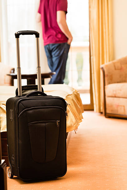 istock Man in hotel room with suitcase by the bed 499335699