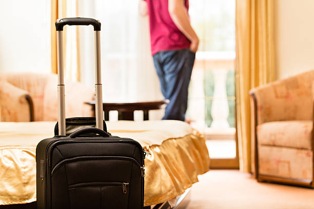 istock Man in hotel room with suitcase by the bed 499335709