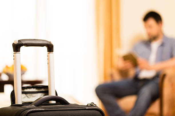 istock Man in hotel room with suitcase by the bed 499335765