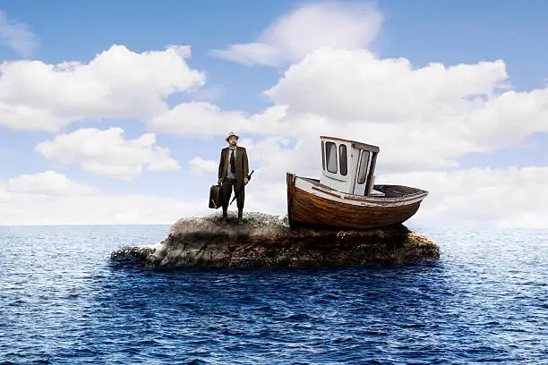 A colour image of a white male traveling man, marooned on a tiny island, with his small boat, holding a suitcase and umbrella. 
