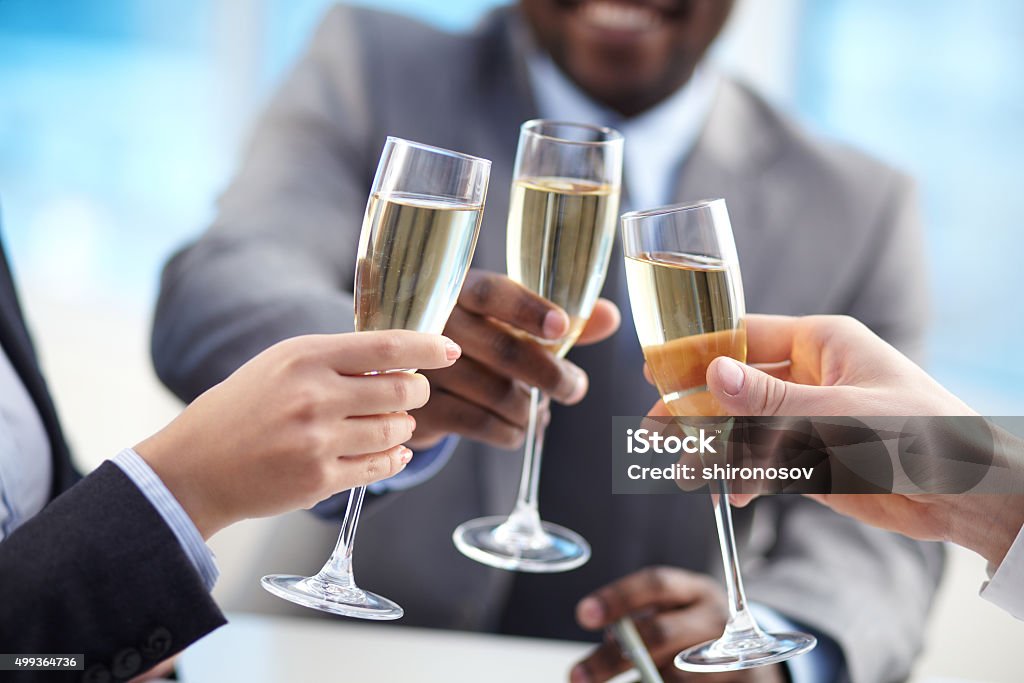 Cheering up Close-up of human hands cheering up with flutes of golden champagne 2015 Stock Photo