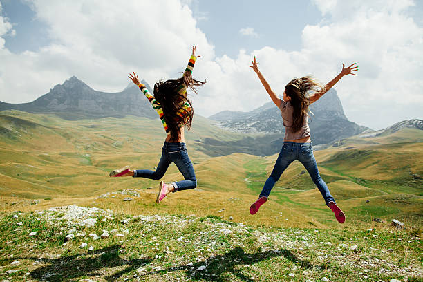 zwei mädchen glücklich sprung in den bergen - austria summer european alps mountain stock-fotos und bilder