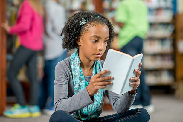 istock Little Girl Reading a Book in the Library 499367828