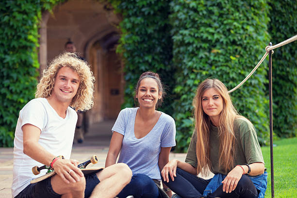 students smiling and looking at the camera Urban students hanging out, waiting for class outside the university. university students australia stock pictures, royalty-free photos & images