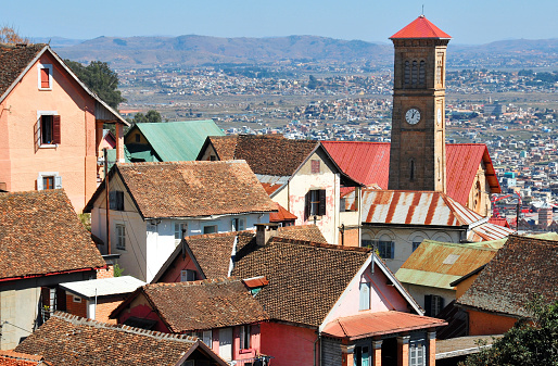 Antananarivo, Madagascar: roofs of the upper town  with the spire of the  FJKM Ambonin 'Ampamarinana church, built in memory of 19th century Christian martyrs -  traditional Malgasy 'trano gasy' two floor houses predominate in the haute ville - Temple protestant d’Ampamarinana - Haute Ville with mountaains in the horizon  - photo by M.Torres