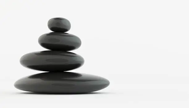 Photo of Stack of black zen stones on white floor.