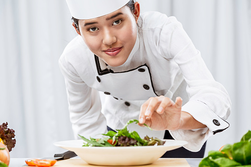 close up of female chef patiently placing salad on a plate