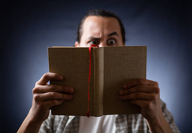 istock young man reading a book in the dark 499389370