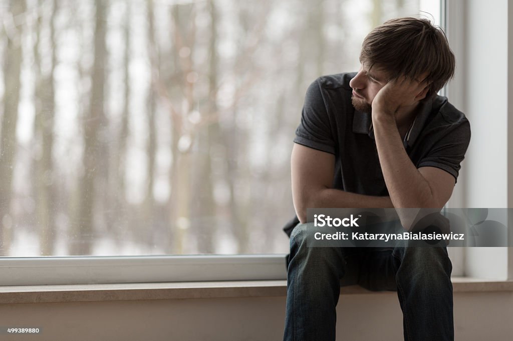 Miserable man sitting and thinking Young miserable depressed man sitting and thinking Men Stock Photo