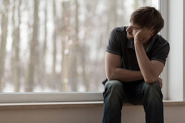 Miserable man sitting and thinking Young miserable depressed man sitting and thinking depression sadness stock pictures, royalty-free photos & images