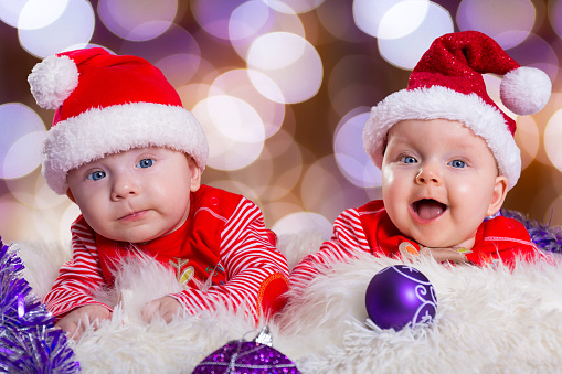 Portrait of baby girl and boy twins in santa costumes for Christmas