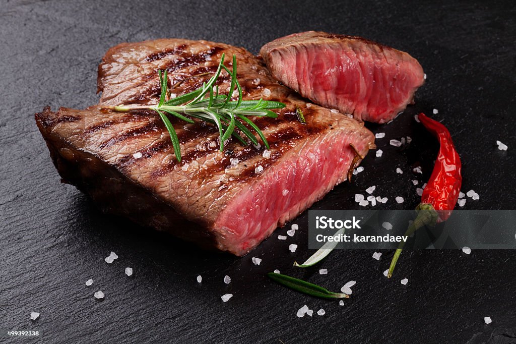 Grilled beef steak with rosemary, salt and pepper Grilled beef steak with rosemary, salt and pepper on black stone plate Meat Stock Photo