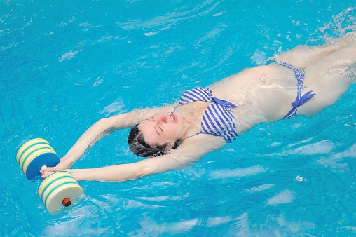 a pregnant woman does her yoga exercises at the pool