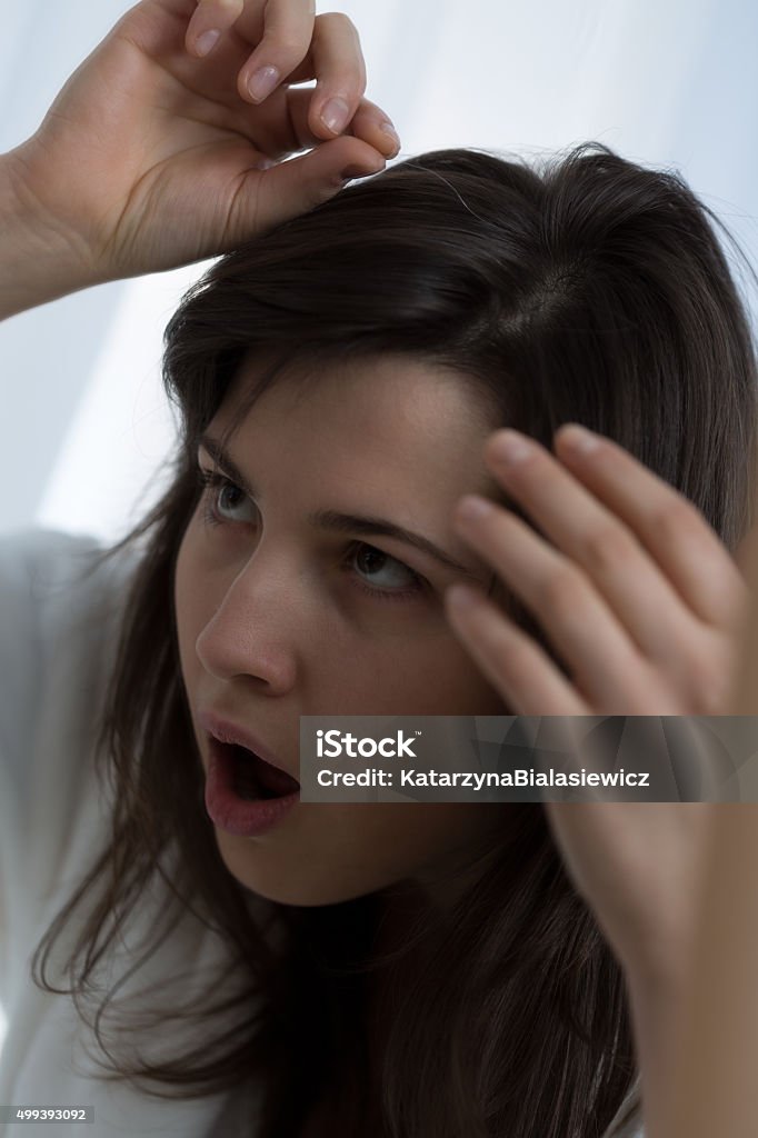 Woman pulling a gray hair Shocked young woman pulling a gray hair Gray Hair Stock Photo