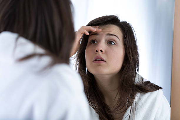 Girl looking in the mirror Girl having problems with skin looking in the mirror wrinkled forehead stock pictures, royalty-free photos & images