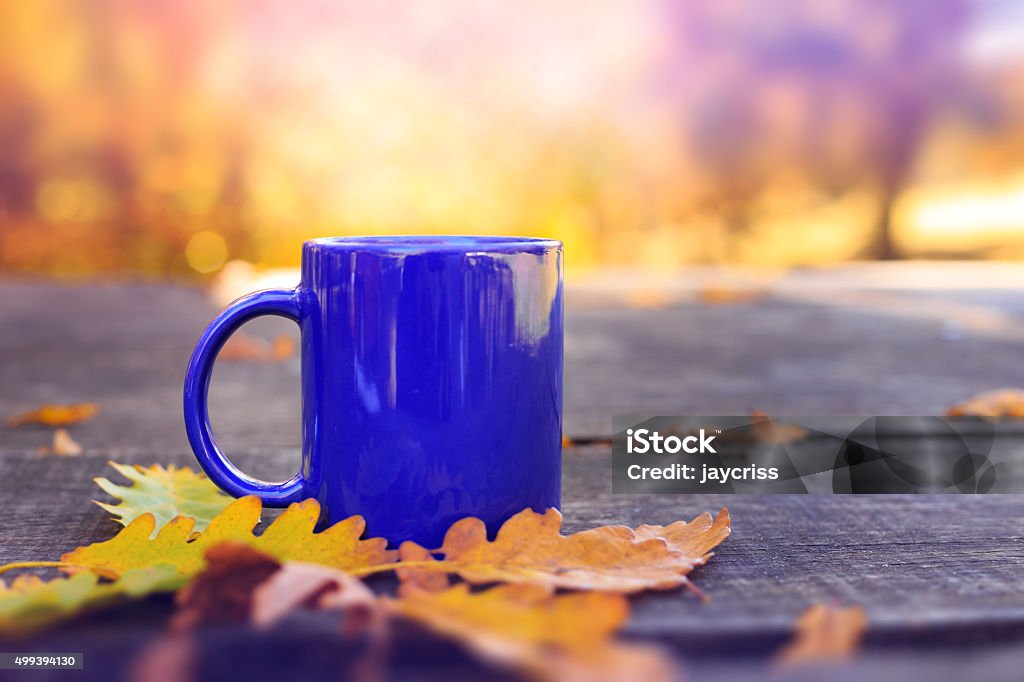 Blue cup on wooden table with autumn blurred background Blue cup on wooden table with autumn blurred background. Outdoor scene. Vintage effect. Autumn Stock Photo