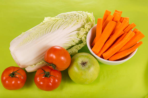 fresh carrots, apples, cabbage and tomatoes on a green background