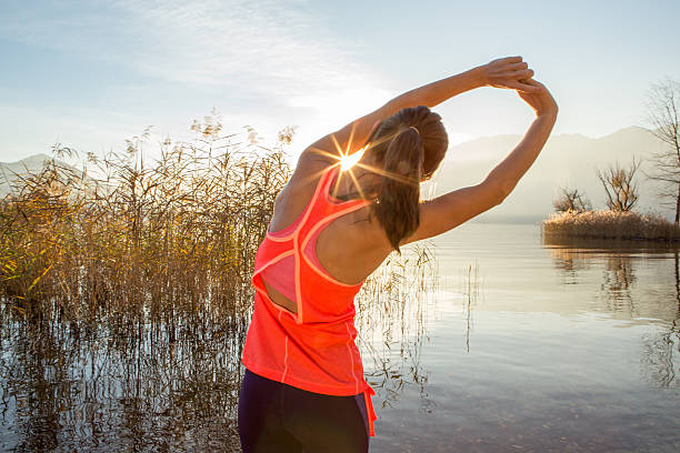 sportiva giovane donna stretching dopo jogging all'aperto - stretching back rear view women foto e immagini stock