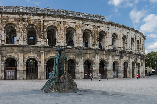 Arles, France - September 11, 2015: Roman Arena (Amphitheater) in Arles and bullfighter sculpture, Provence, France