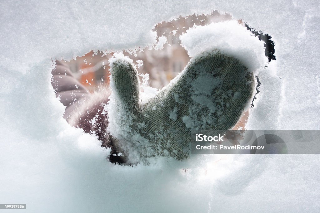 hand in mitten cleaning window of car hand in mitten cleaning window of car from the snow, inside view Snow Stock Photo