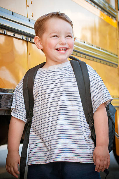 istock Happy young boy in front of school bus 499400807