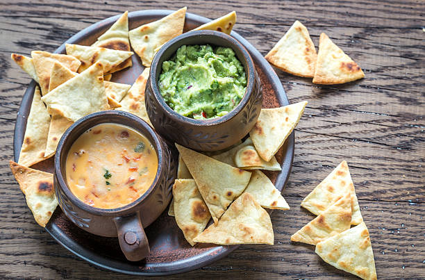 Bowls of guacamole and queso with tortilla chips