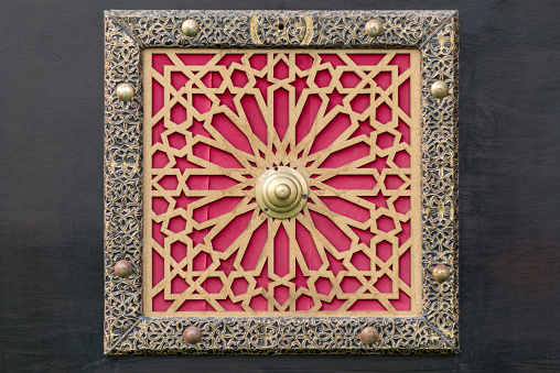 Traditional Islamic pattern made from brass as found on a door in a Middle Eastern country with red background